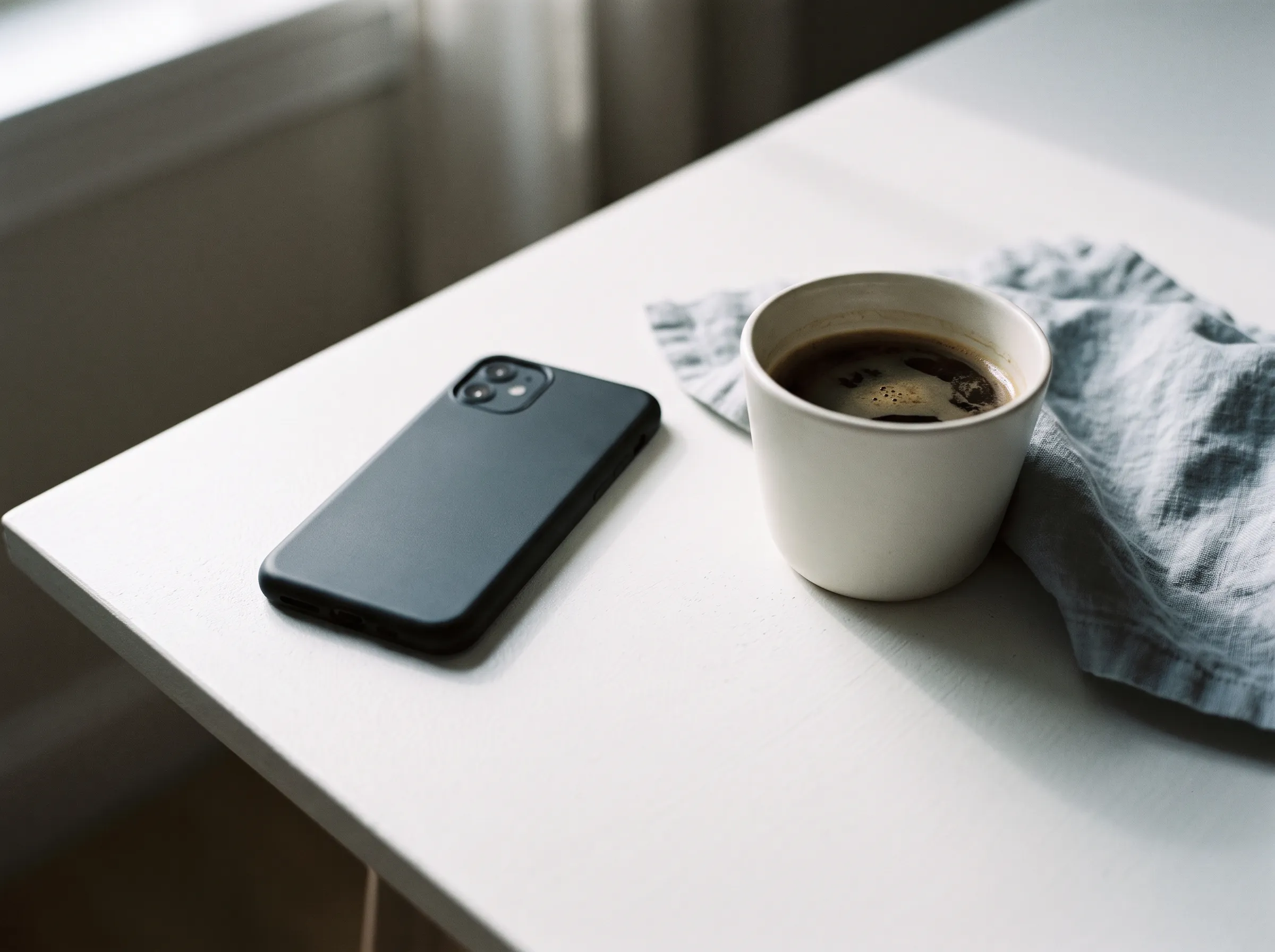 Téléphone posé face contre une table blanche